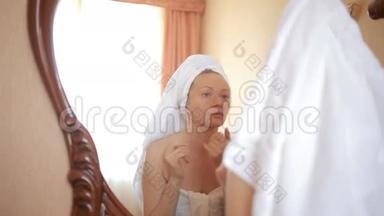 女人敷<strong>面膜保湿</strong>护肤霜在脸上照镜子。